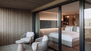 Une chambre moderne avec un grand lit, deux chaises blanches et une petite table.