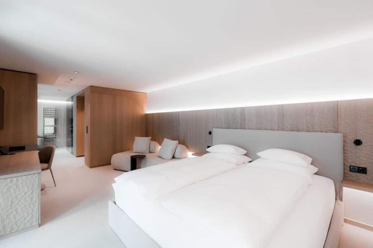 A modern hotel room with a large bed, a desk, and a seating area.