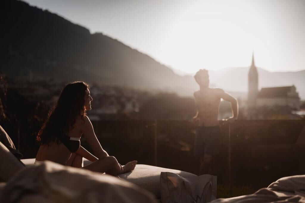 Ein Bett mit Blick auf ein weit entferntes Gebäude und Berge.