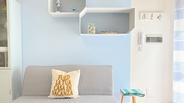 Ein Schlafzimmer mit Bett, einem Kissen mit Text, einem kleinen Tisch und Regalen an der Wand.