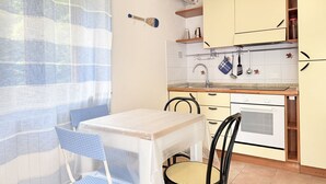 Eine Küche mit Tisch und Stühlen, einem Herd und einem Fenster mit Vorhang.