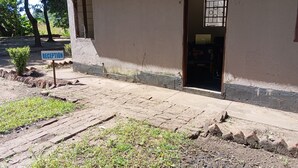 A building with a reception area, a paved entrance, and a small garden. - blue Waxbill Lodge  (South Luangwa National Park)