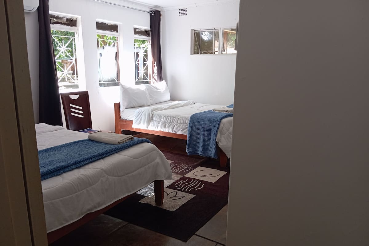 Ein Zimmer mit zwei Betten, einem Fenster mit Blick und einer Tür.