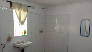 A bathroom with a sink, a shower, and a window with a curtain. - blue Waxbill Lodge  (South Luangwa National Park)