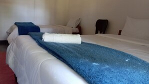 A hotel room with two beds, a blue blanket on one bed, and a white towel on the other. - blue Waxbill Lodge  (South Luangwa National Park)