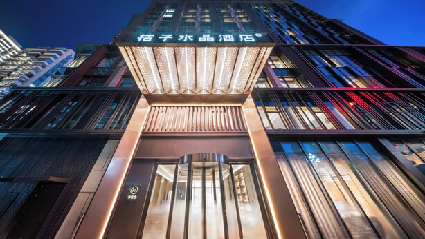 A modern hotel entrance with a revolving door, glass facade, and illuminated signage. - Crystal Orange Shenzhen Luohu Port (Shenzhen)