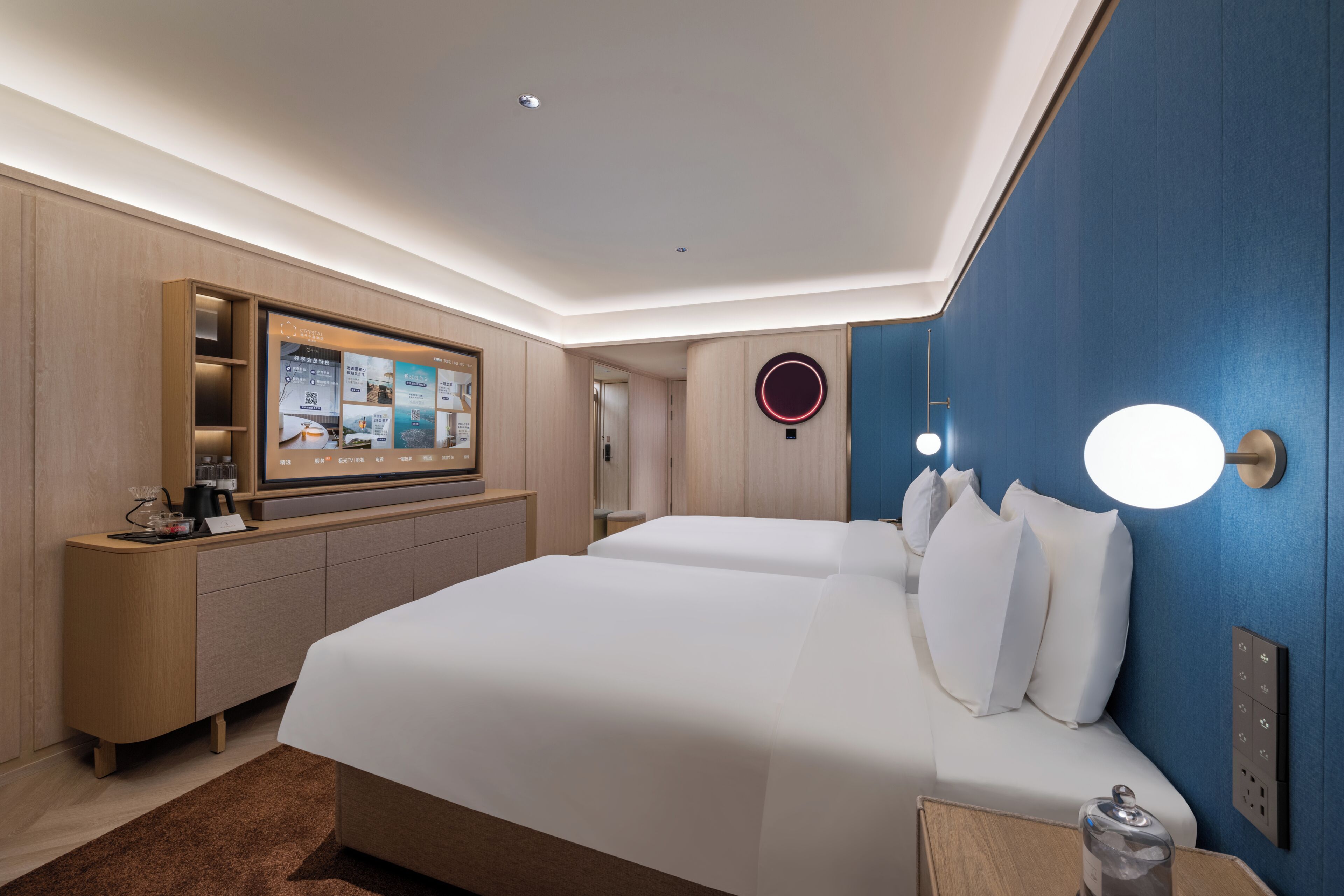 Une chambre d’hôtel moderne dotée d’un grand lit, d’un téléviseur fixé au mur et d’un meuble en bois contenant une machine à café.