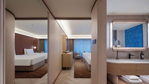 A hotel room with a bed, a desk, a chair, a mirror, and a bathroom with a sink and towel rack. - Crystal Orange Shenzhen Luohu Port (Shenzhen)