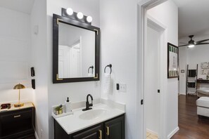 A bathroom with a vanity, a large mirror with lights, a towel rack, and a clock. - FW15, Prime Golf View 1BR - No Stairs! Walk to Pool & Amenities (Branson West)