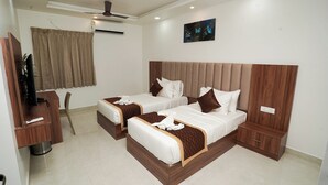 Una habitación de hotel con dos camas, un televisor, un ventilador de techo y un cuadro en la pared.