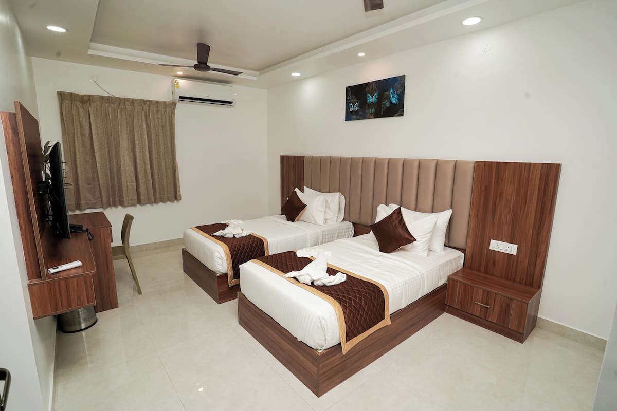 A hotel room with two beds, a TV, a ceiling fan, and a painting on the wall.
