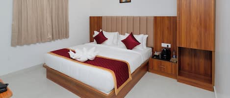 A hotel room with a bed, a wardrobe, a bedside table, and an air conditioning unit.