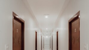 Un pasillo largo y estrecho con puertas de madera a cada lado y un piso brillante y reflectante.