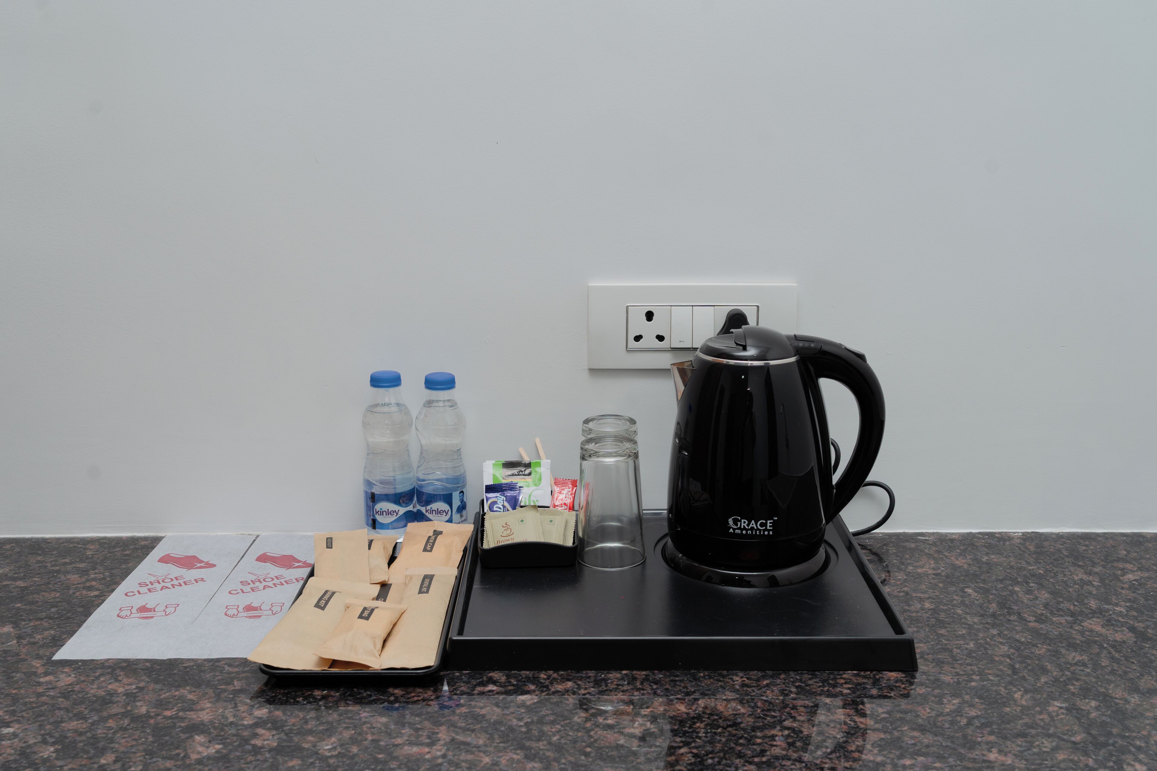 A kitchen counter with a coffee maker, water bottles, a glass, and a packet of tissues.