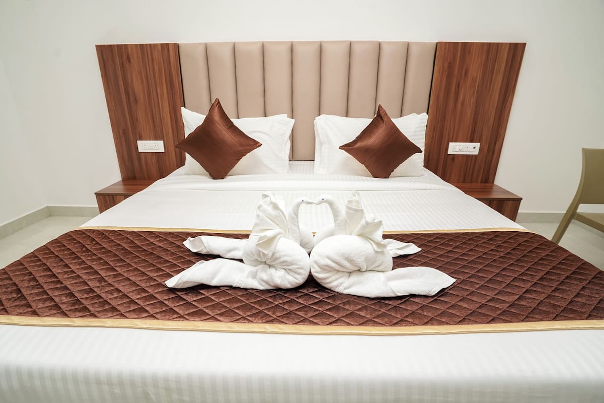 A bed with a quilted brown bedspread, two white pillows, and a wooden headboard.