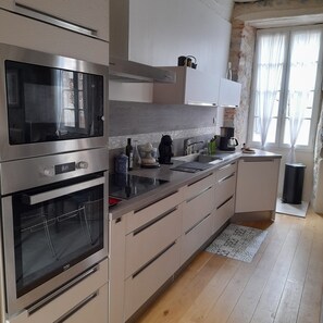 Eine moderne Küche mit Edelstahlgeräten, einem Backofen, einer Mikrowelle und einem Spülbecken.