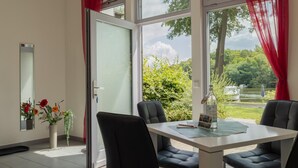Una habitación con una mesa, sillas, una ventana y vistas a follaje.