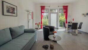 Una sala de estar moderna con un sofá, una mesa redonda, una silla y un comedor con mesa y sillas.