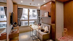 Una habitación de hotel moderna con sofá, una mesa de comedor, televisión y vistas a la ciudad.