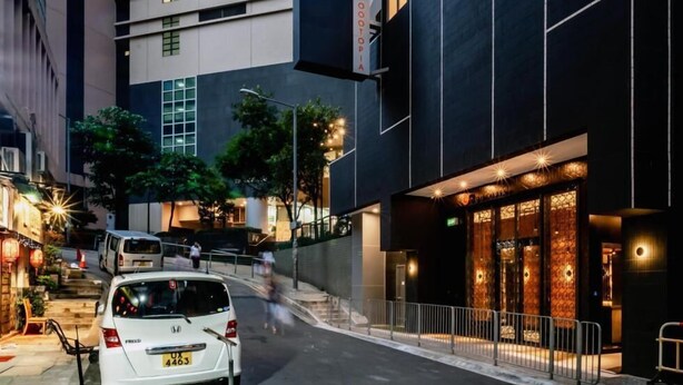 Un hotel moderno con un letrero llamativo, una entrada bien iluminada y un coche estacionado en la parte delantera.