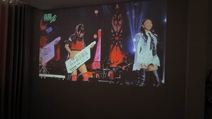 A projection of a band performing on stage with a keyboard, guitar, and drums. - Peanuts Home Le Lai - Chic Local Stay, Steps to Ben Thanh & Bui Vien (Ho Chi Minh city)