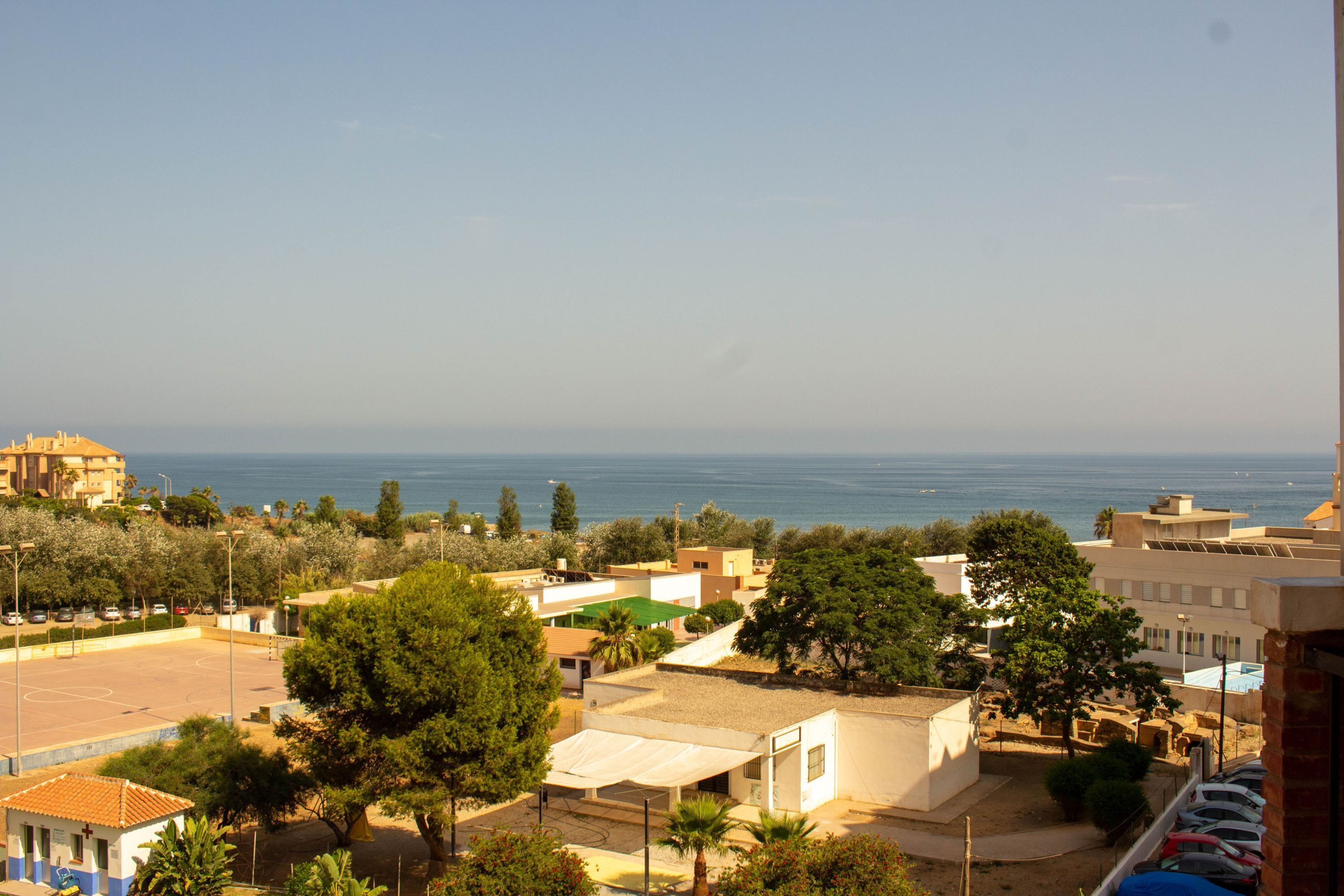 Un quartier résidentiel avec des immeubles, des arbres et une vue sur la mer.