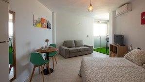 Una habitación con cama, sofá, mesa de comedor con sillas, televisor y obras de arte en la pared.