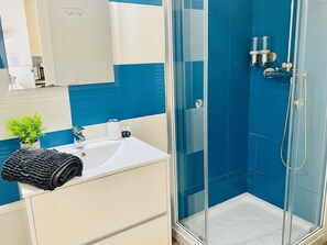 A bathroom with a glass-enclosed shower, a sink with a towel, and a mirror. - Capri 403 by At Home Costa del Sol (Torrox)