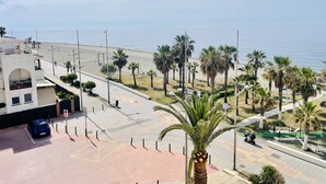 Een kustgebied met een parkeerplaats, palmbomen en uitzicht op zee.