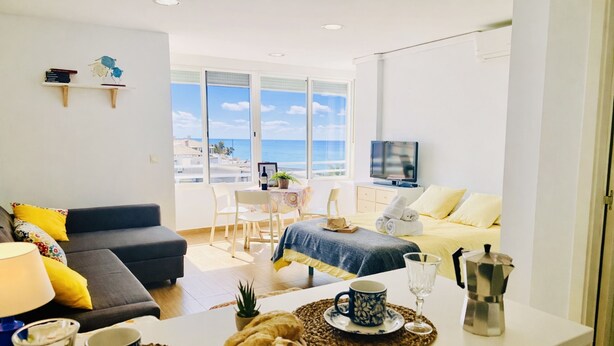 Een moderne woonkamer met een bank, eettafel en uitzicht op het strand.