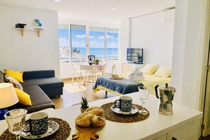 A modern living room with a sofa, dining table, and a view of the beach. - Capri 403 by At Home Costa del Sol (Torrox)
