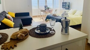 Een moderne woonkamer met een bank, salontafel en een eethoek met een tafel en stoelen.