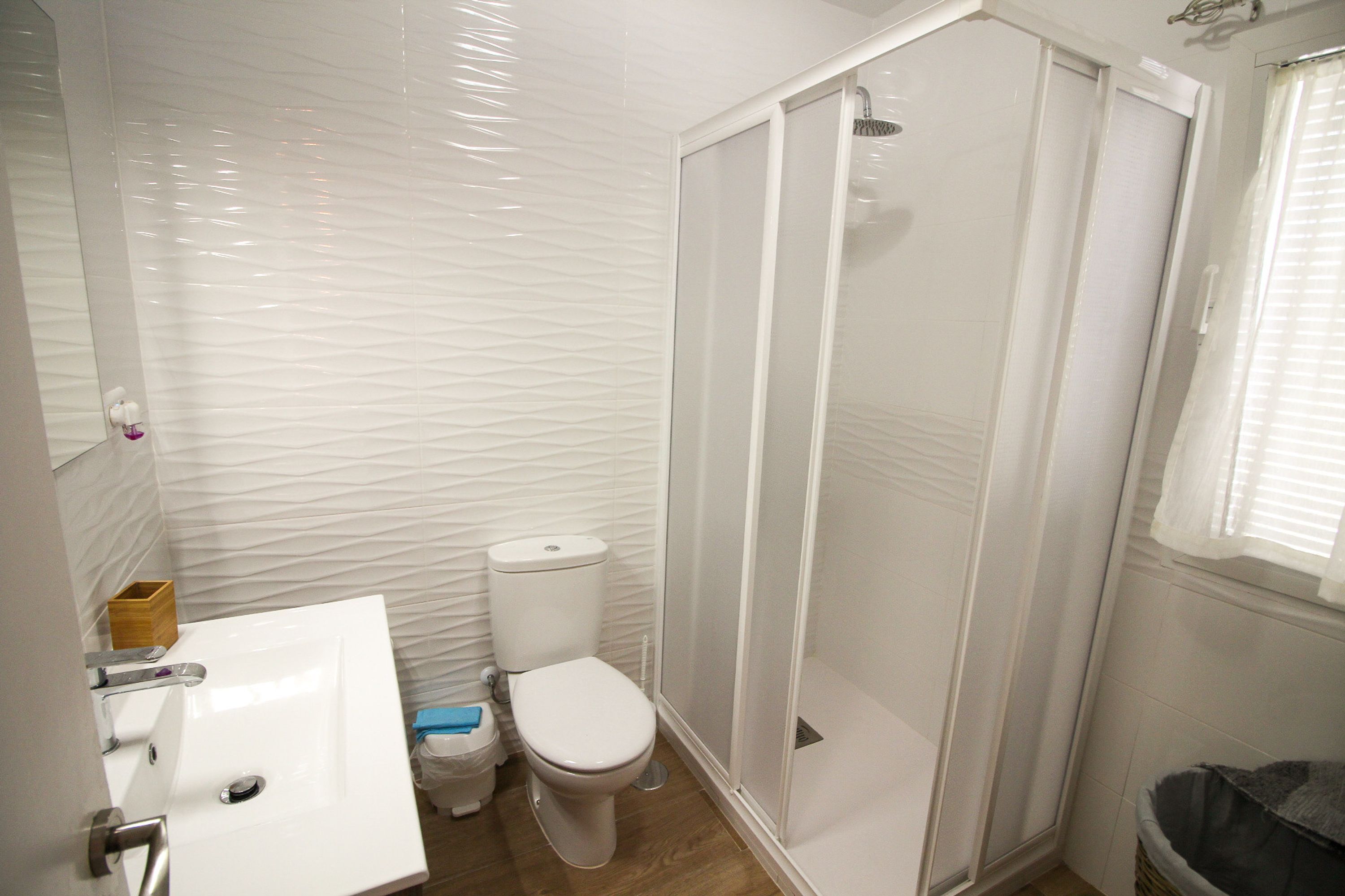 Ein Badezimmer mit weißem Waschbecken, WC und Duschkabine.