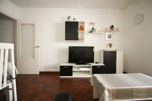 Una habitación con televisión, armarios, una mesa y una puerta.