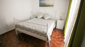 A bedroom with a bed, nightstands, a wall-mounted air conditioner, and a painting. - P Andaluz 670 by At Home Costa del Sol (Torrox)