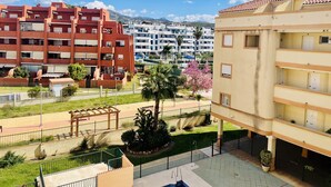 A residential area with multi-story buildings, a swimming pool, and a park with palm trees. - Albatros 1 by At Home Costa del Sol (Algarrobo)