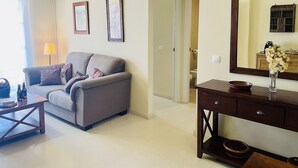 A living room with a sofa, coffee table, and a wooden side table with a vase. - Albatros 1 by At Home Costa del Sol (Algarrobo)