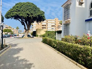 A residential street with parked cars, a large tree, and multi-story buildings. - P Andaluz 921 by At Home Costa del Sol (Torrox)