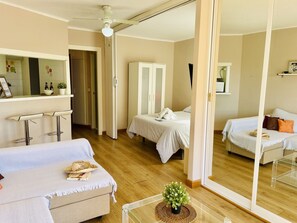 Hotelkamer met een bed, een bank, een kleine tafel met een plant, een spiegel en een plafondventilator.