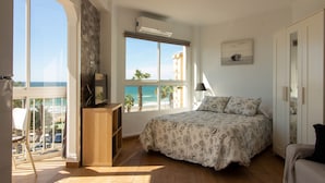A bedroom with a bed, a TV on a stand, a window with a view of the sea, and a balcony. - Ruselo 308 by At Home Costa del Sol (Torrox)
