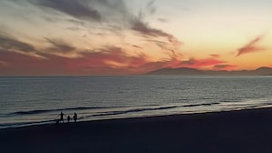 A beach scene with a sunset, calm sea, and silhouettes of two people walking. - Ruselo 308 by At Home Costa del Sol (Torrox)
