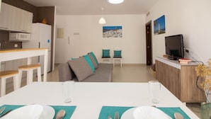 Um espaço moderno com área de refeições, cozinha e espaço para sentar.