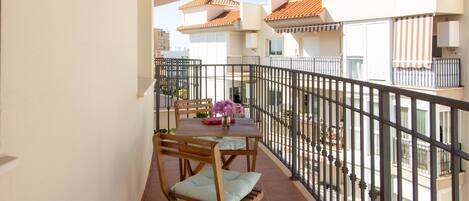 A balcony with a table, chairs, and a flower vase.