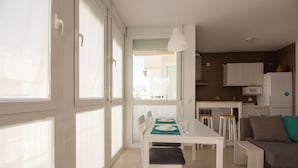 Uma cozinha moderna com armários brancos, uma mesa de jantar com cadeiras e um sofá.