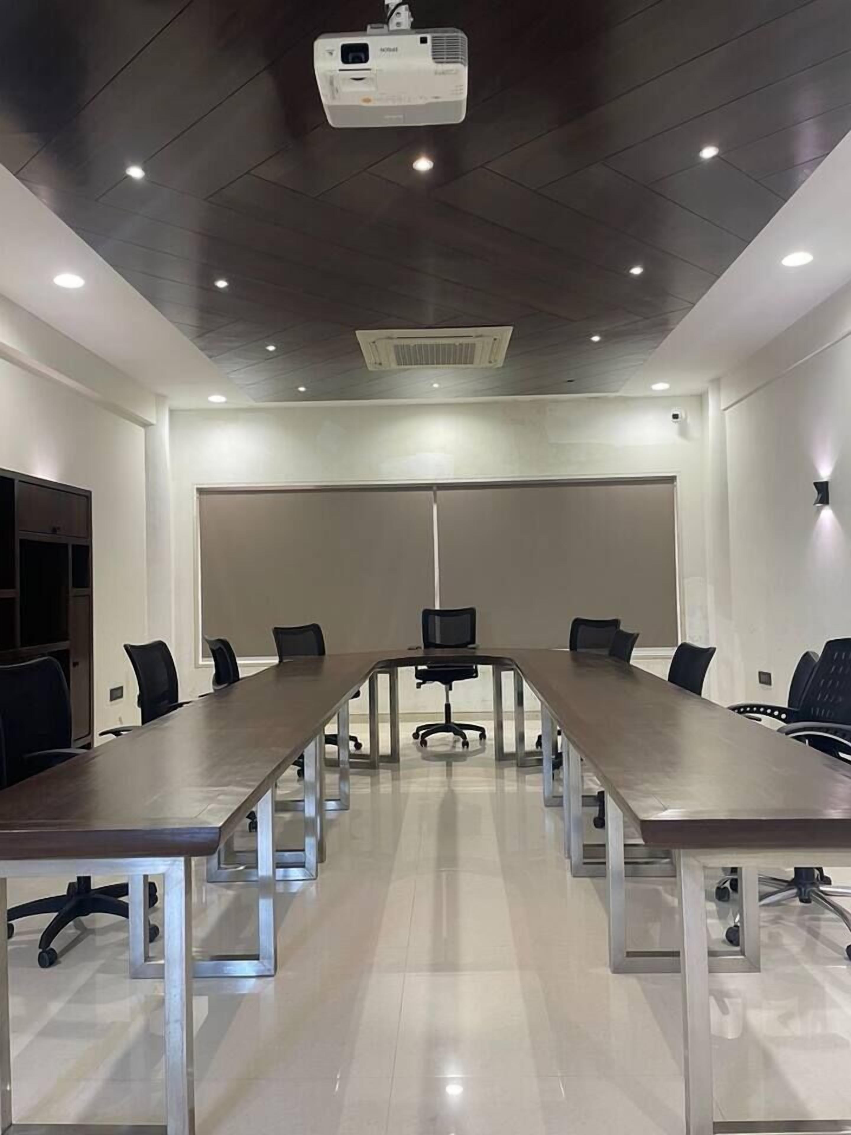 A conference room with a long table, chairs, a projector, and a whiteboard.