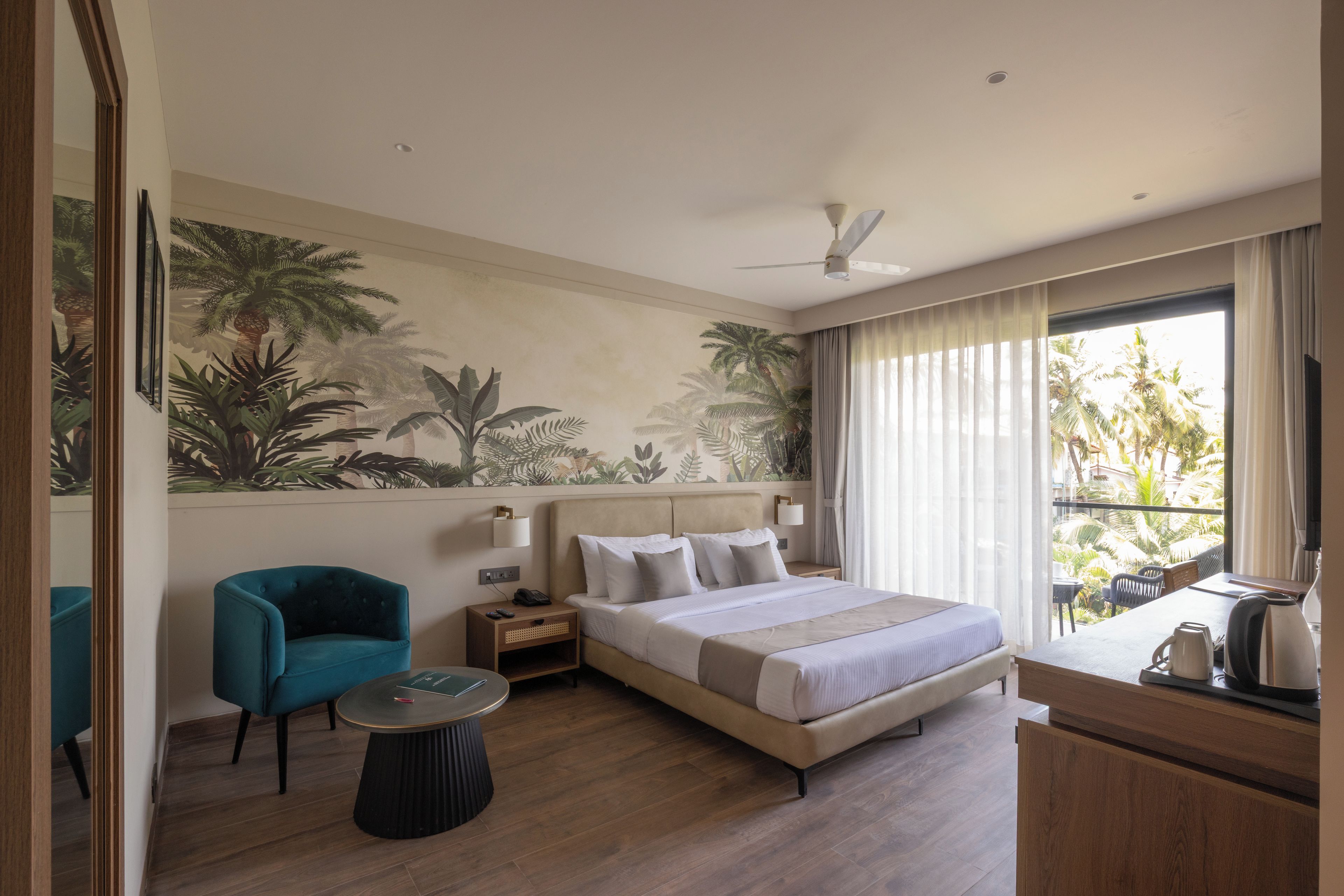 Una habitación de hotel con una cama, una silla, una mesita de noche, un escritorio y una ventana con cortinas.