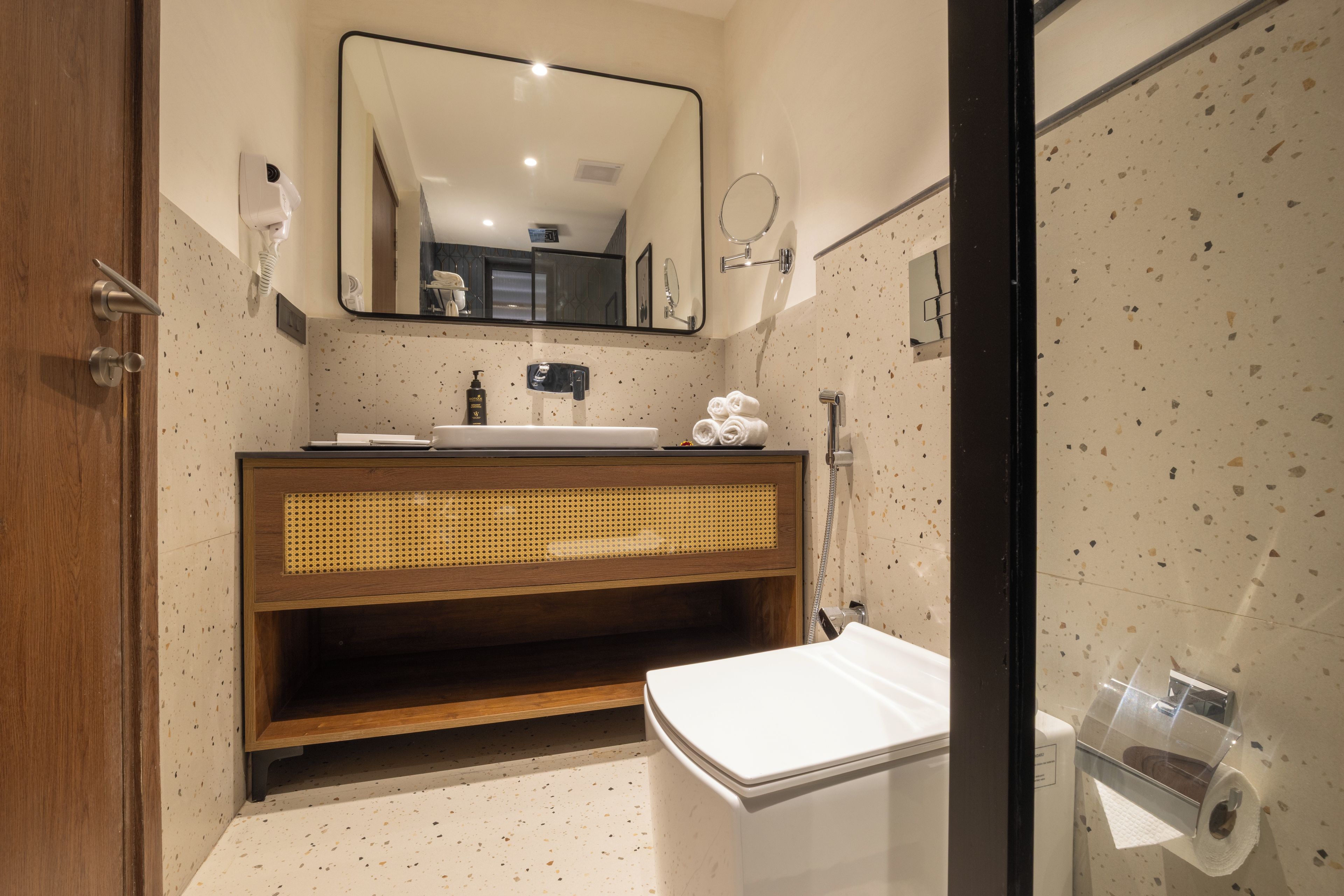 A modern bathroom with a wooden vanity, a large mirror, and a glass shower enclosure.
