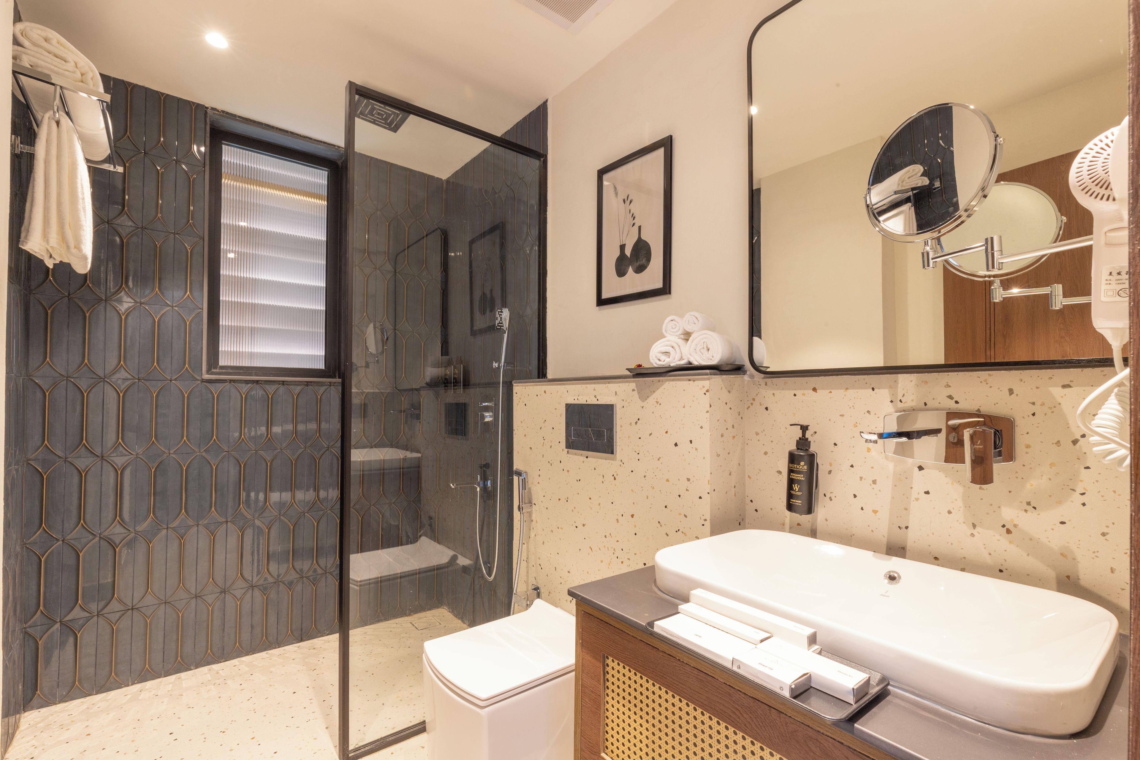 A modern bathroom with a glass-enclosed shower, a large mirror, and a sink with a towel rack.