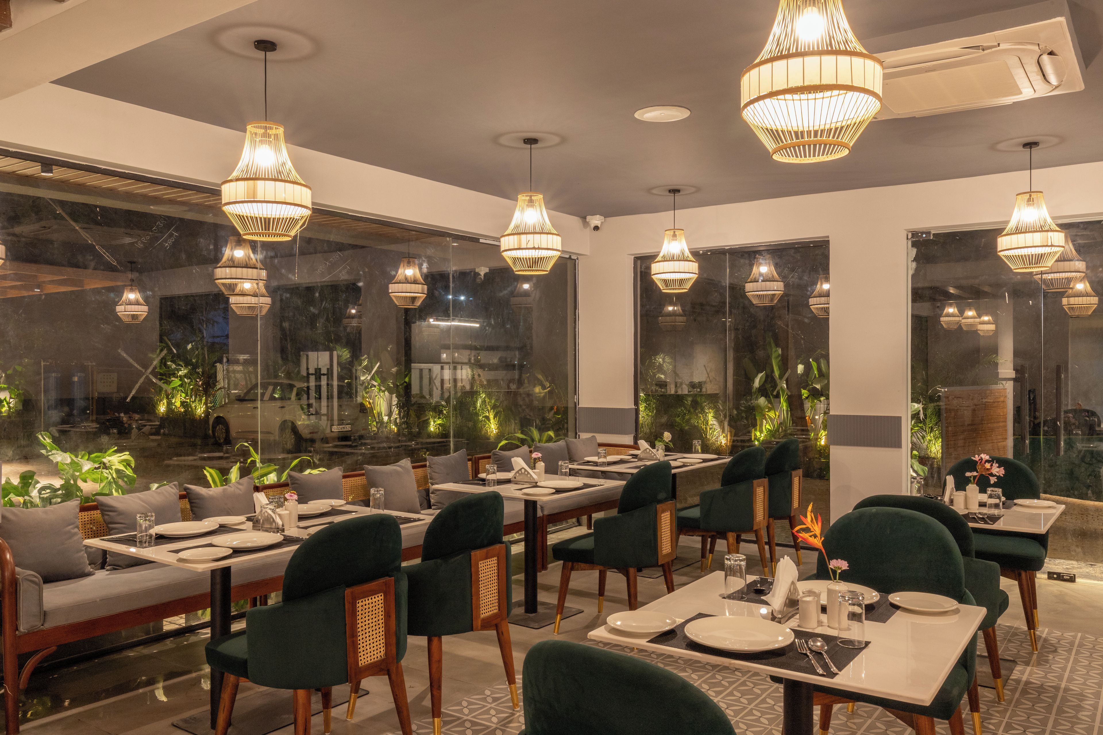 A restaurant with multiple dining tables, chairs, and hanging pendant lights.
