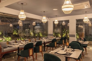 Un restaurante con varias mesas, sillas e iluminación colgante.